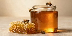 Jar of golden honey and dripping honeycomb with bees crawling