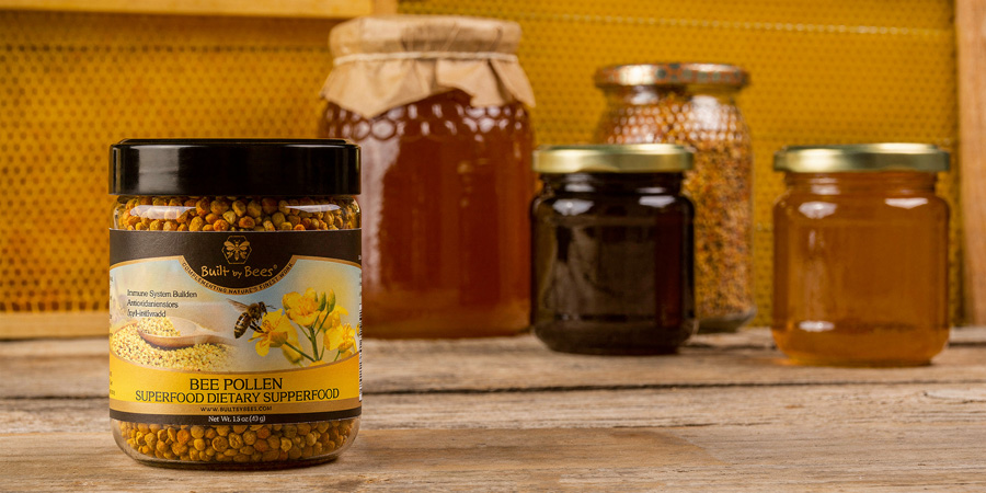 Jar of bee pollen on wooden table with jars of honey and honeycomb